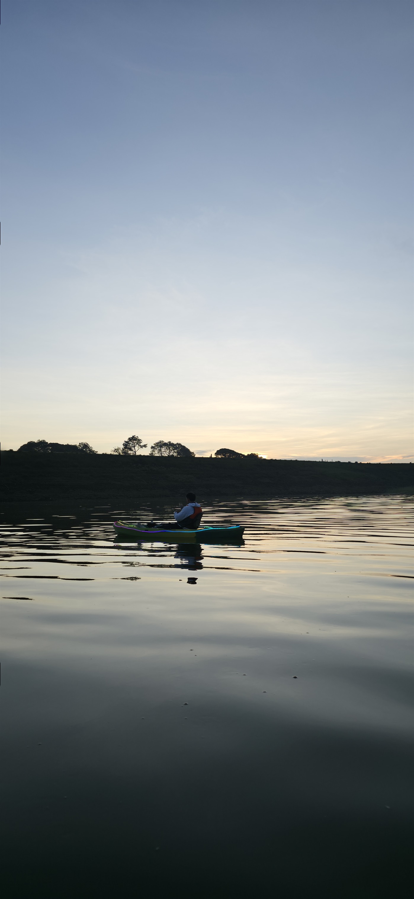 Una persona en kayak sobre la presa durante el amanecer, con reflejos de luz en el agua