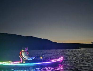 Persona en kayak iluminado con luces de colores durante la hora azul