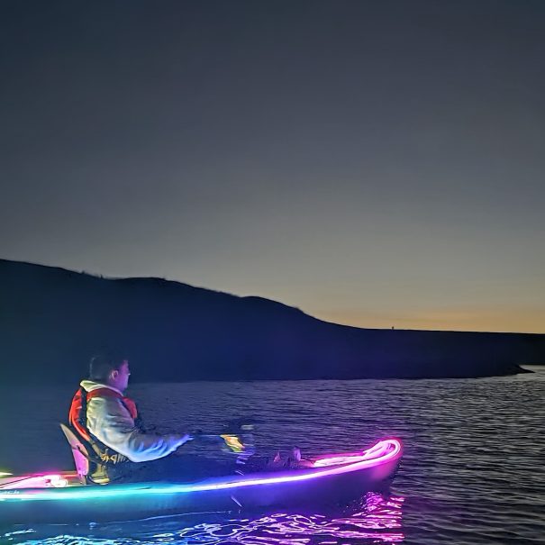 Persona en kayak iluminado con luces de colores durante la hora azul